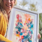 Woman holding a framed colorful abstract painting outdoors