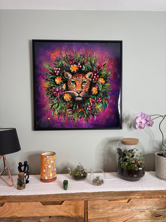 Framed artwork with vibrant wreath and leopards head in centre