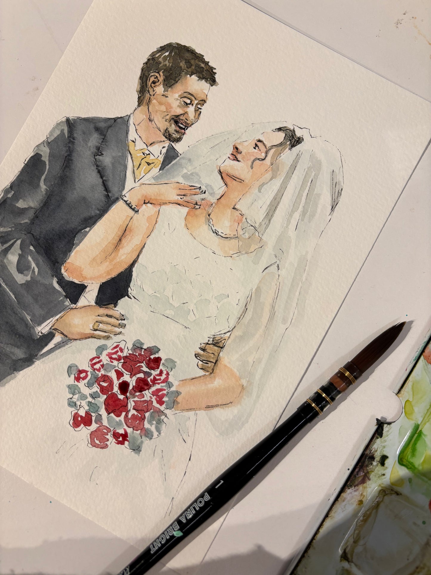 A custom watercolor wedding portrait of a bride and groom on textured paper, with a paintbrush resting on the bottom right corner.