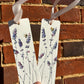 Two white tags with lavender  and bee designs held against a brick background