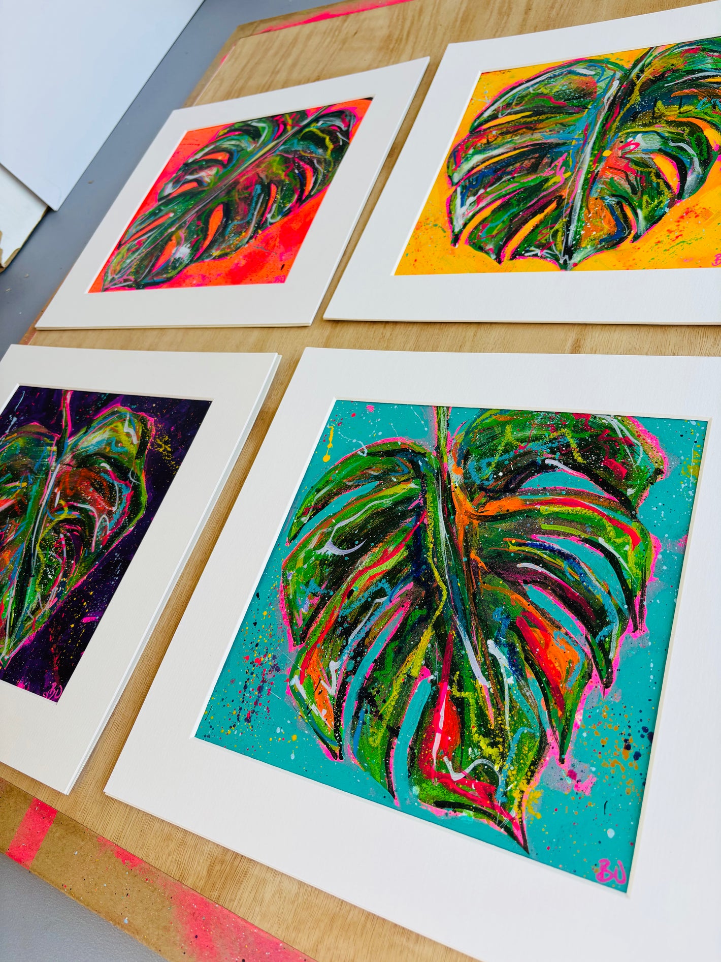 Four colorful leaf paintings on a wooden surface