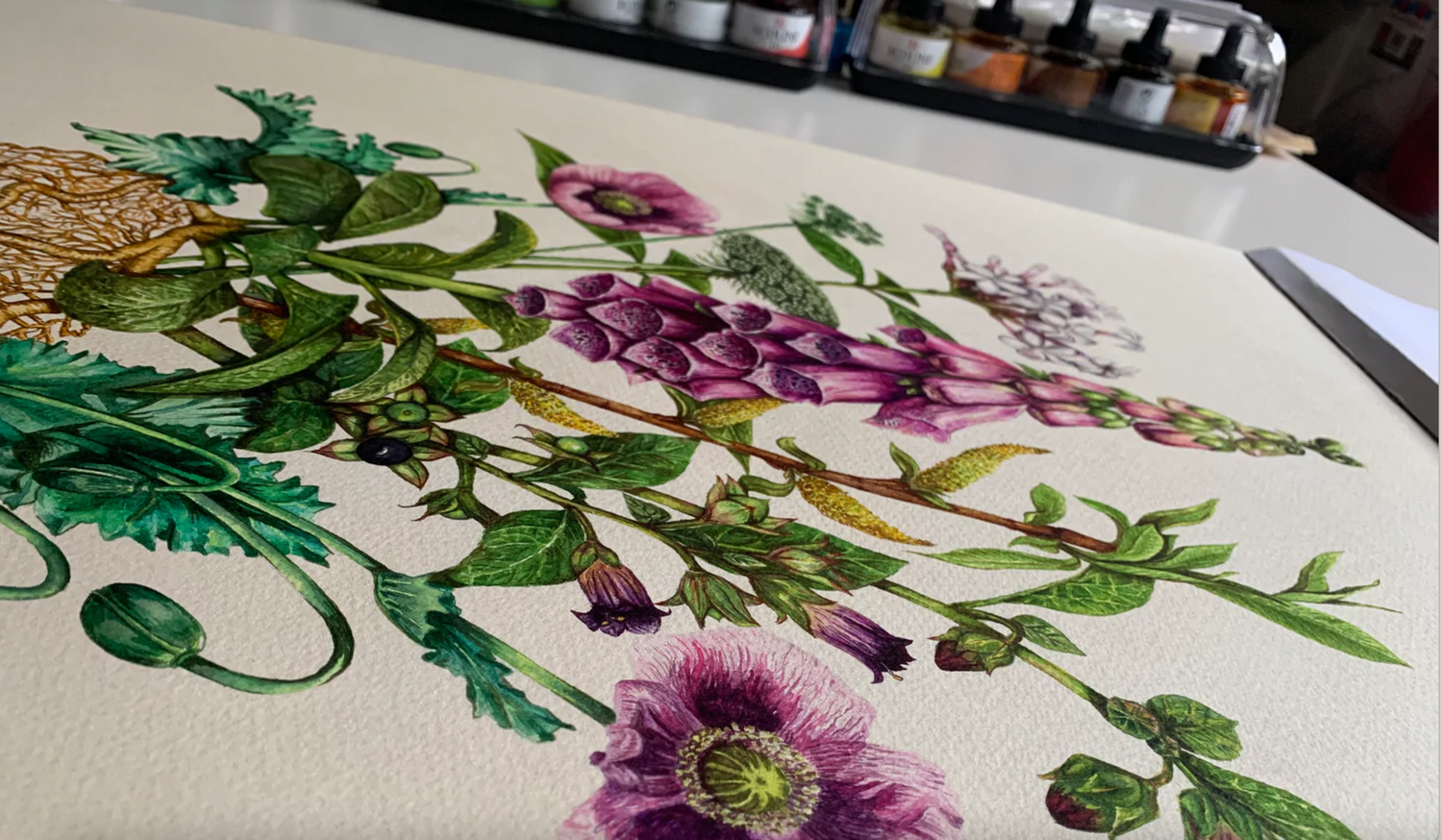 Floral illustration on a computer screen with art supplies in the background